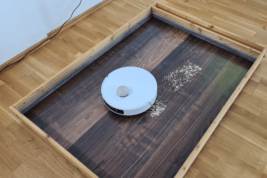 Пылесос Dreame L20 Ultra убирает овсянку на ламинате пол во время теста.